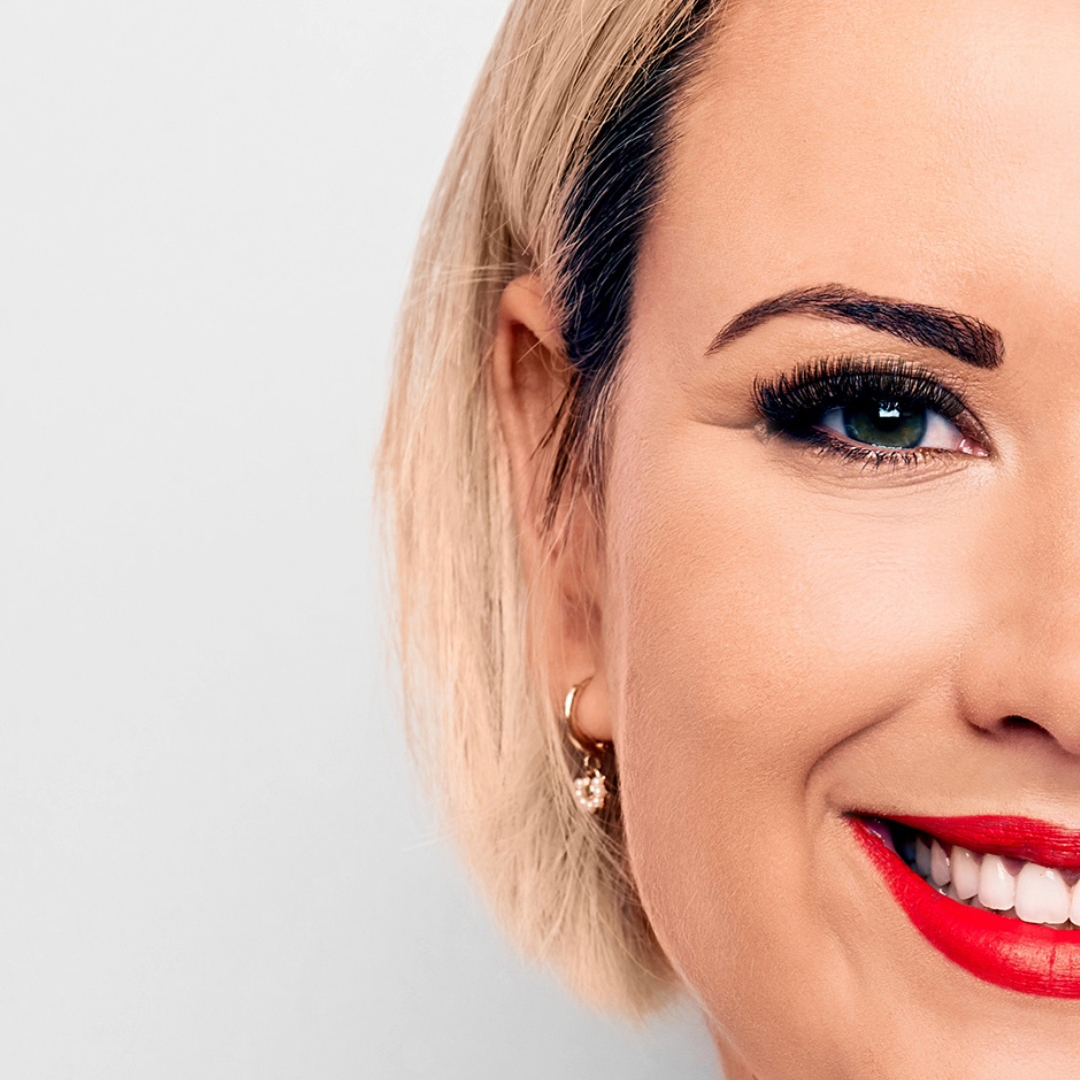 half shot of woman's smiling face with tinted brows
