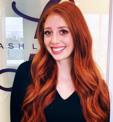 photo of an eyelash extension stylist in the salon with a beautiful smile and long red hair