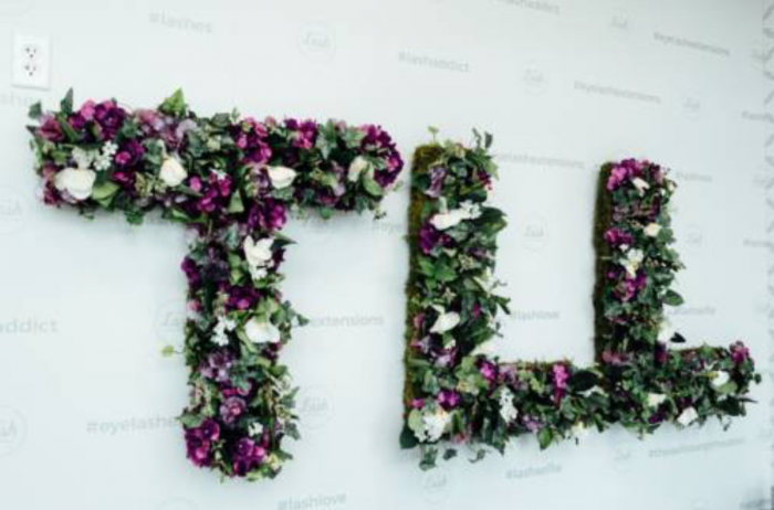TLL spelt out in purple and white flowers hanging on the wall